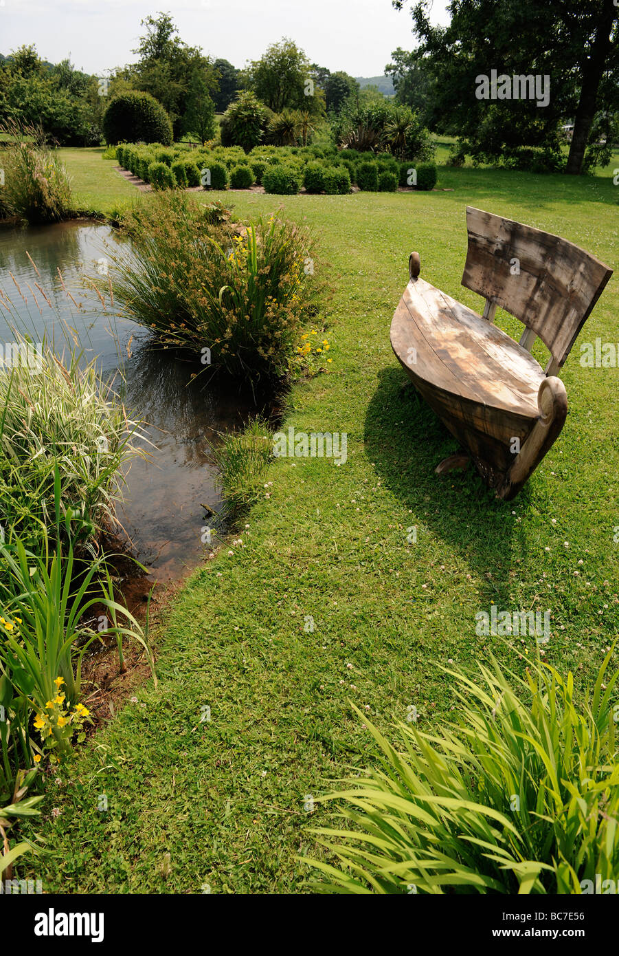 Barca sede sagomata dal lago di un paesaggistico giardino inglese in Stoberry Park, Somerset, Regno Unito Foto Stock