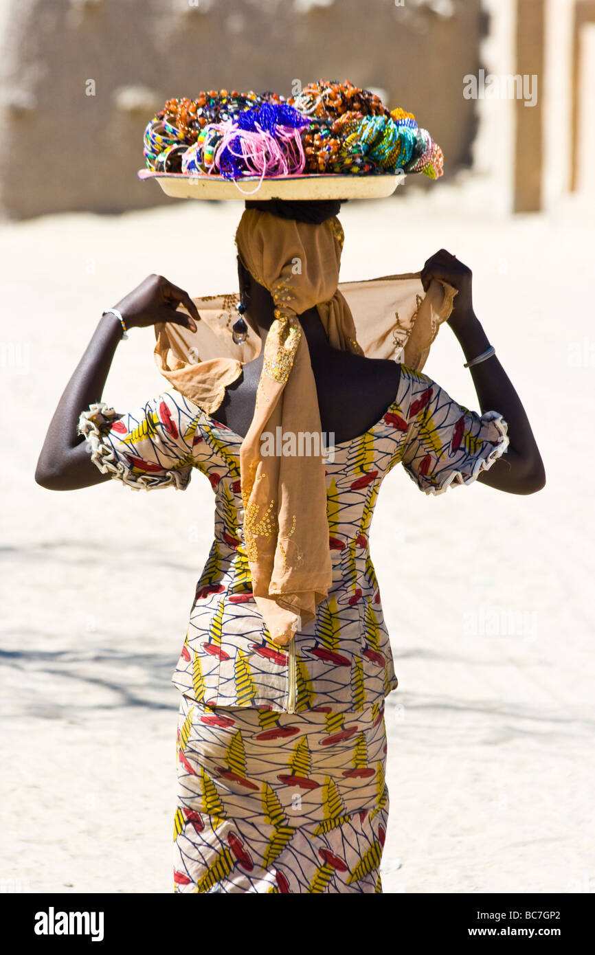 Donna con negozio di souvenir equilibrato sul suo capo in Timbuktu Mali Foto Stock