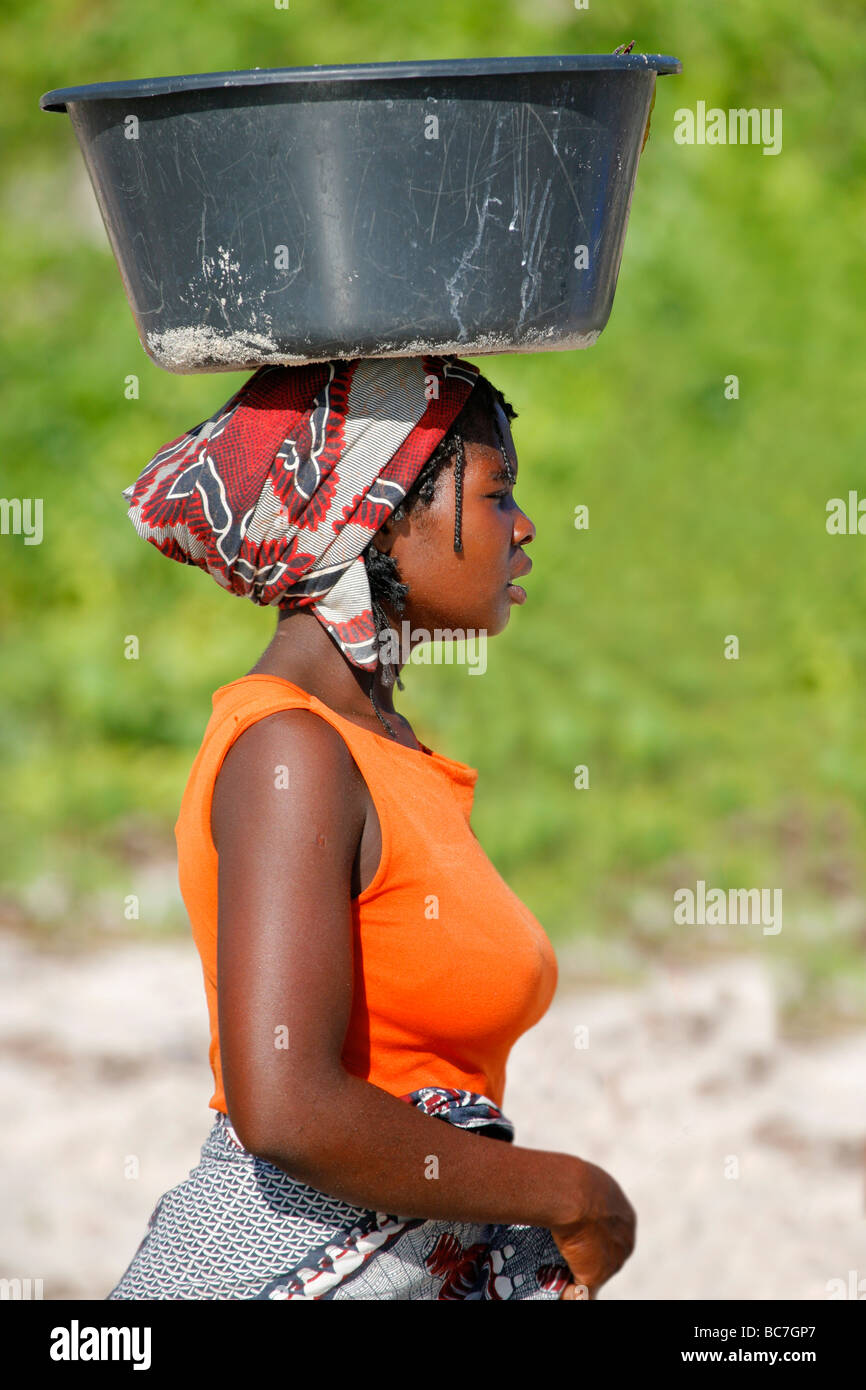 La donna che porta un cestello sul Vilanculos Beach Foto Stock