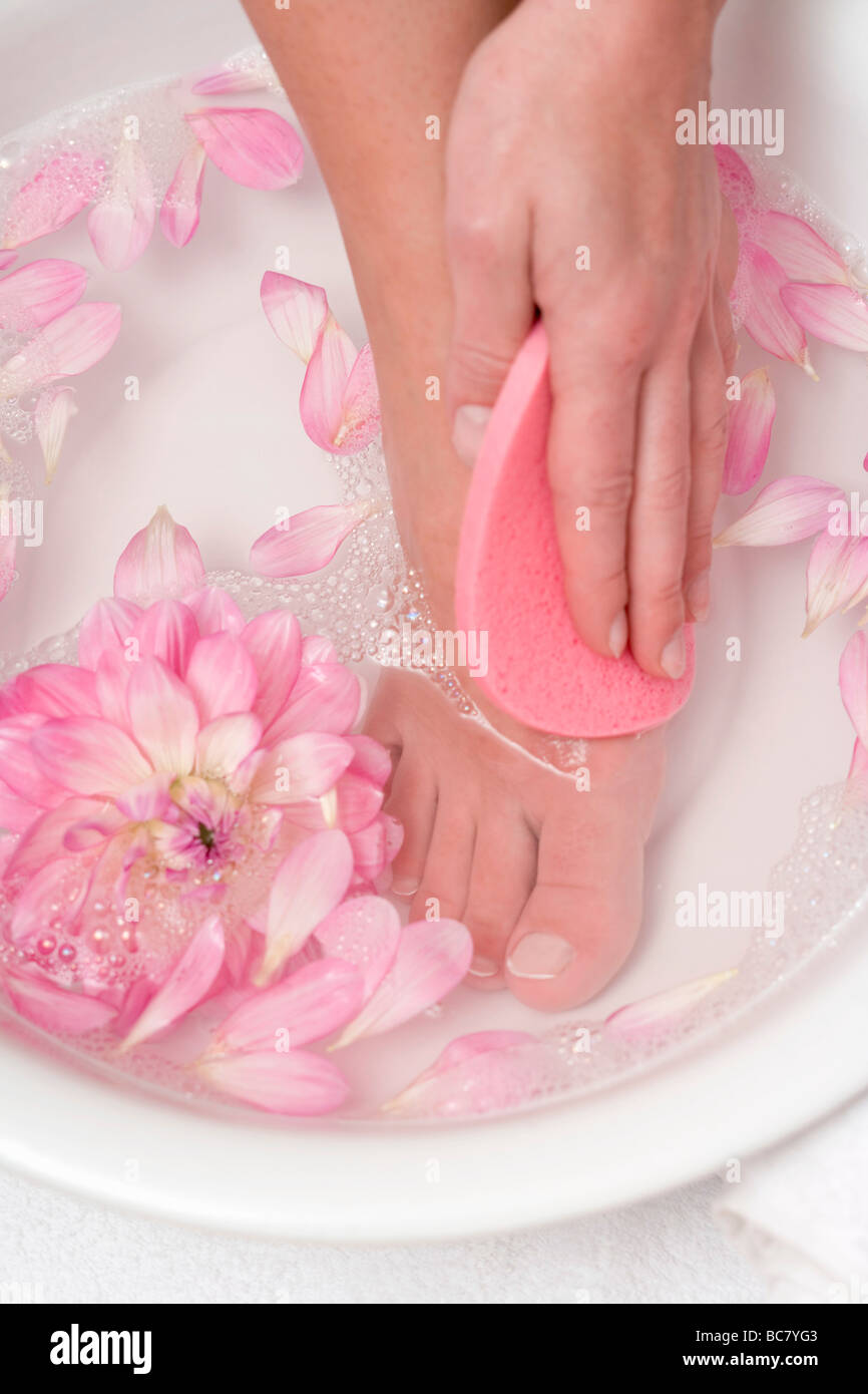 Donna lavando il suo piede con spugna rosa - Foto Stock