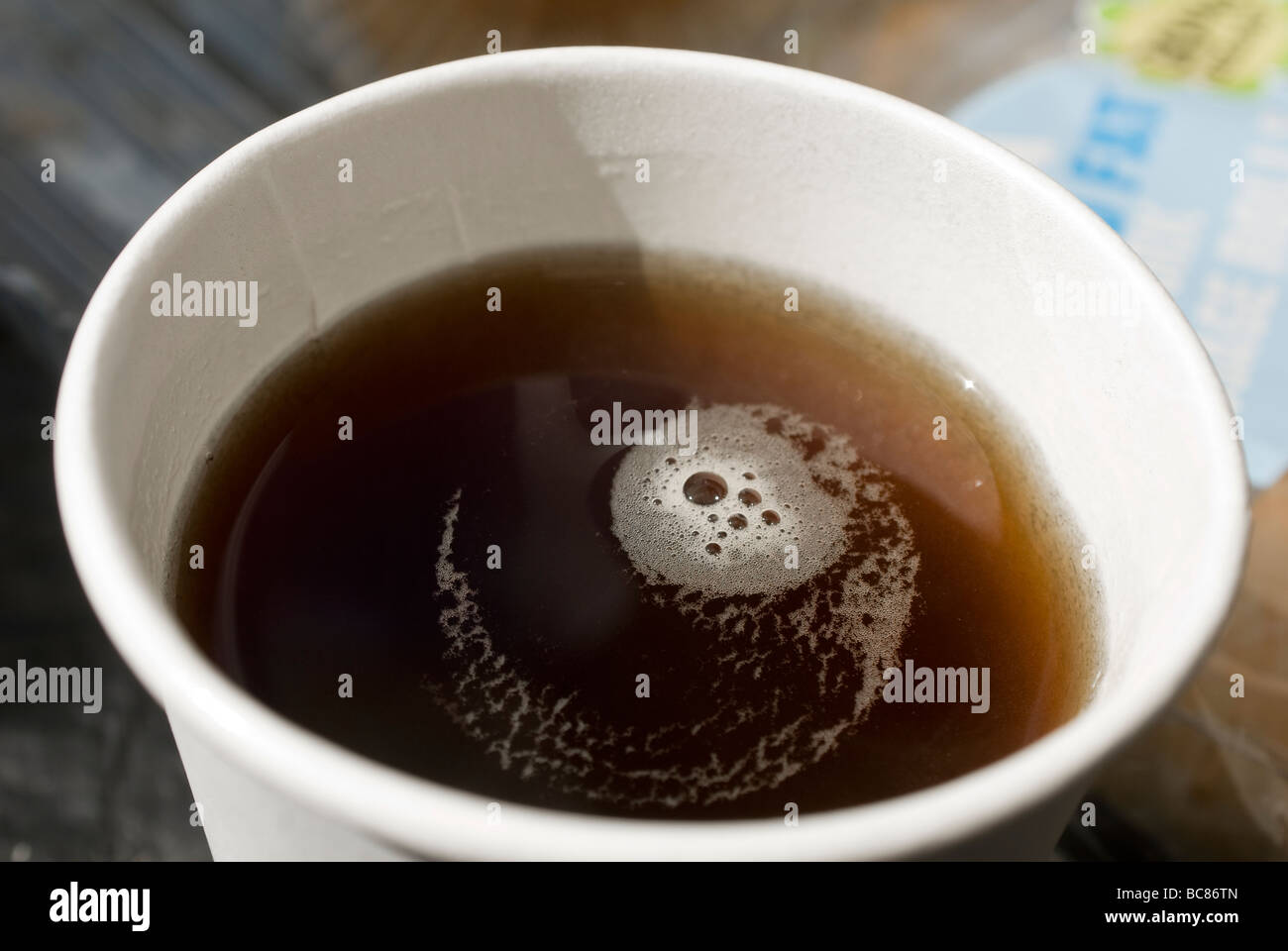 Bolle galleggianti su un caffè nero in un bicchiere in polistirene Foto Stock