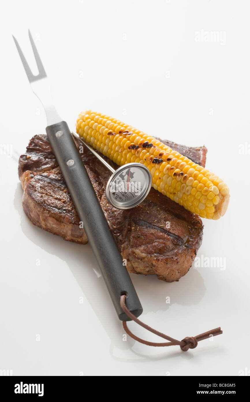 Bistecca di manzo con sulla pannocchia di mais, forchettone & termometro - Foto Stock