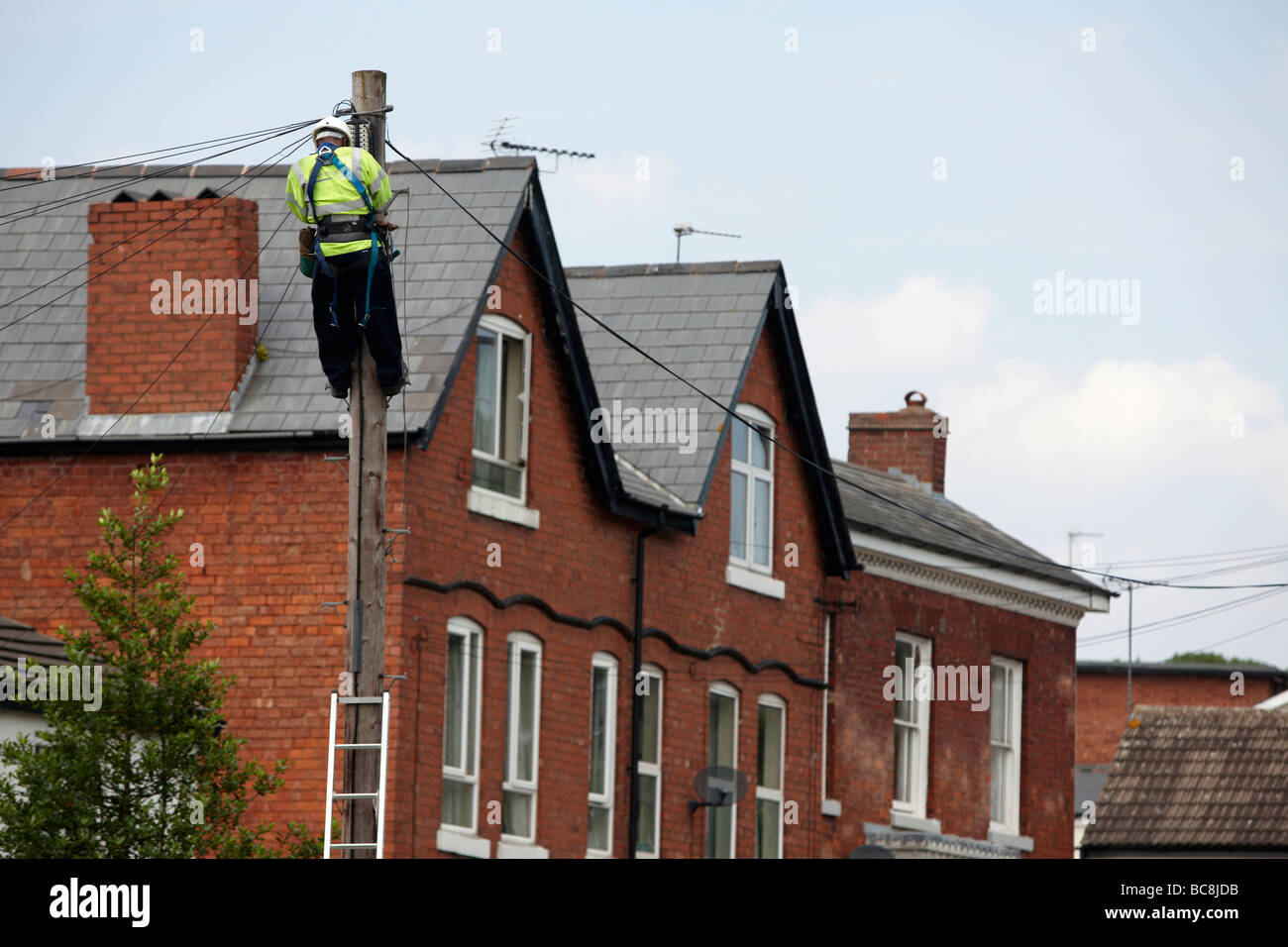 British Telecom engineer opera su una linea telefonica alla sommità di un palo telefonico Foto Stock