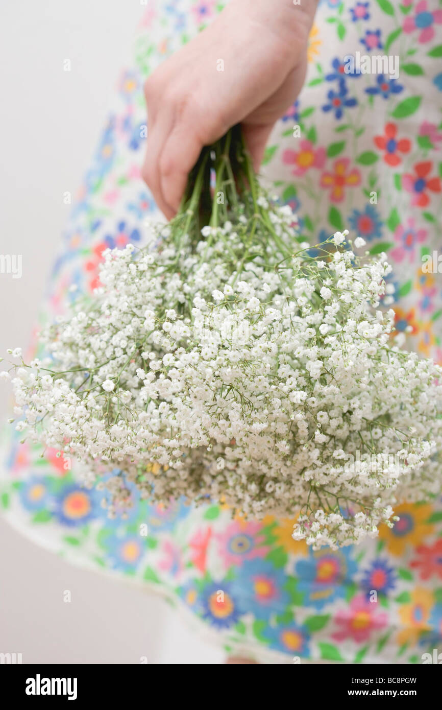 Donna in abito fiorito holding gypsophila - Foto Stock