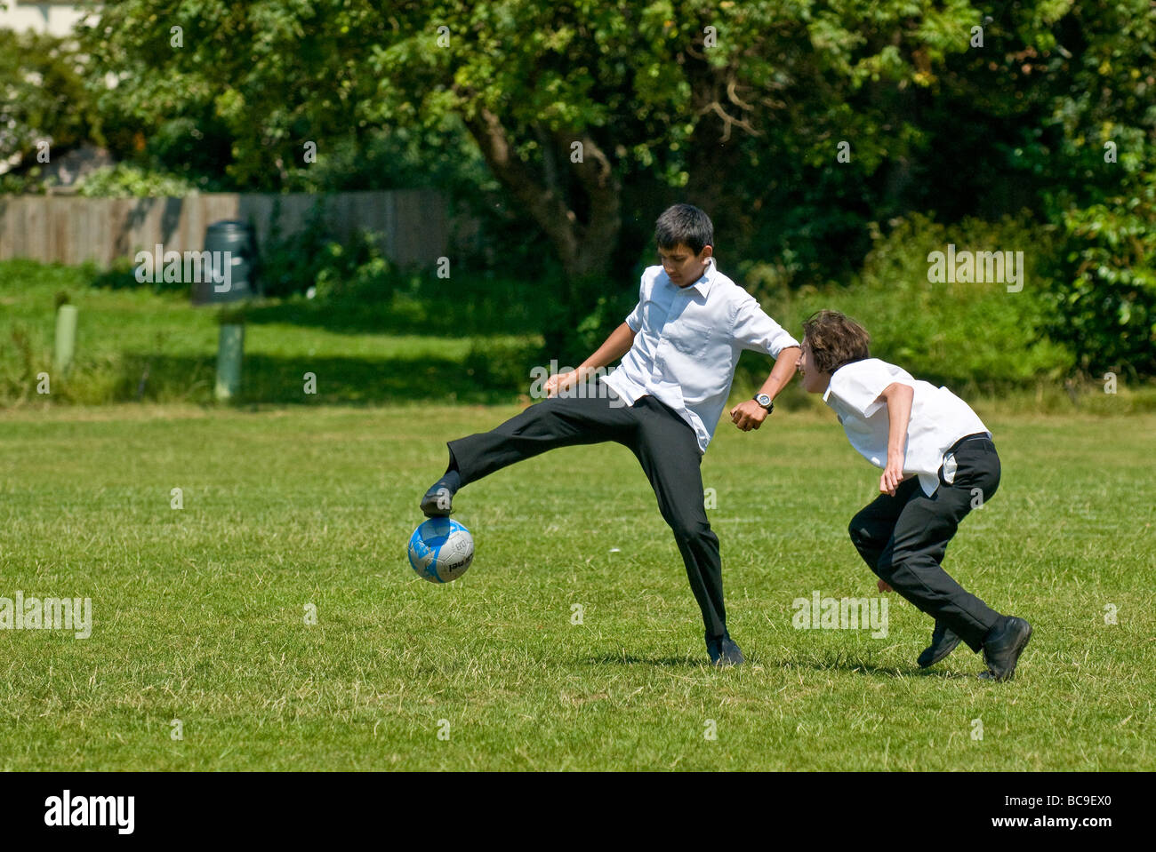 Due scolari a giocare a calcio su una scuola campo da gioco. Soccer Foto Stock