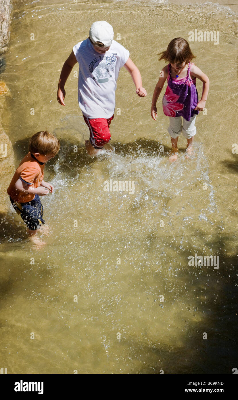 Bambini che giocano in Arkansas River lungo un marciapiede in Salida Colorado USA Foto Stock