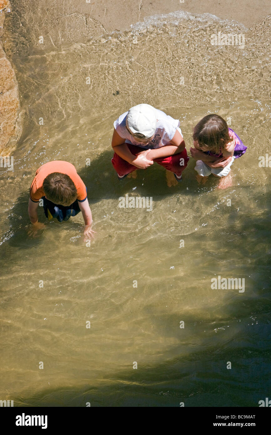 Bambini che giocano in Arkansas River lungo un marciapiede in Salida Colorado USA Foto Stock