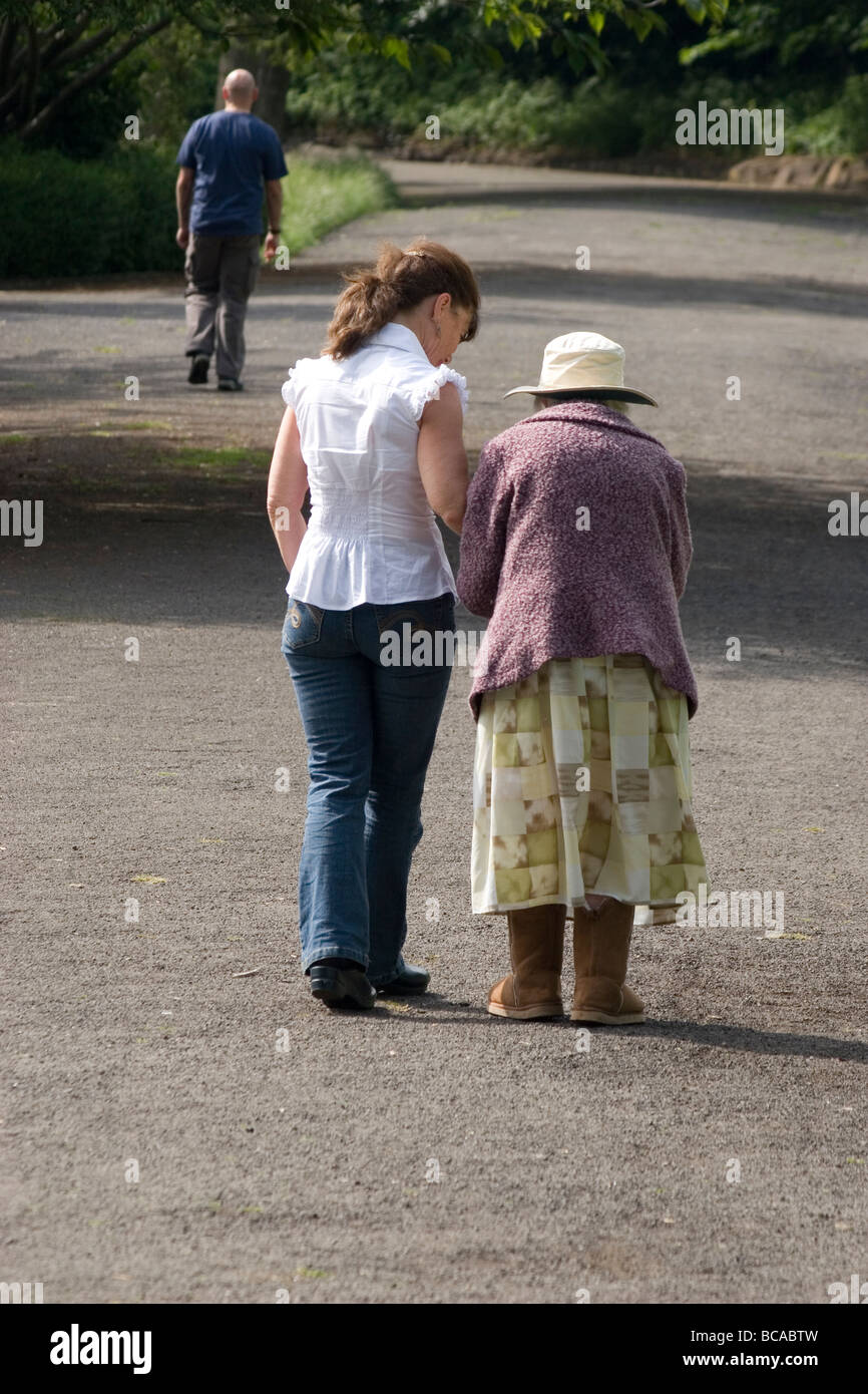 Donna che cammina con molto anziana signora in posizione di parcheggio Foto Stock