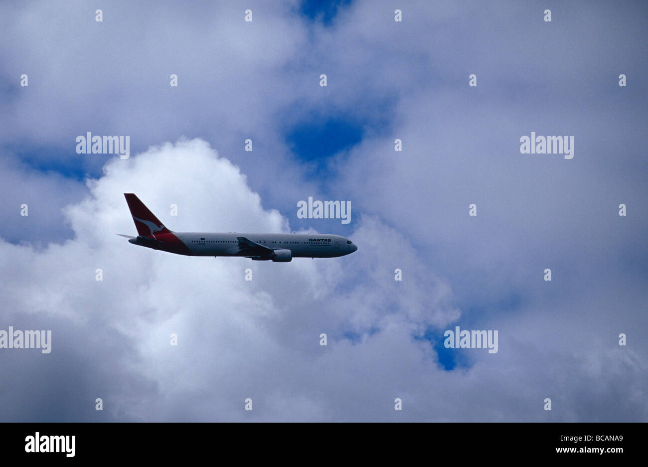 Un gigante Qantas jumbo jet nave passeggeri battenti in nuvole temporalesche. Foto Stock