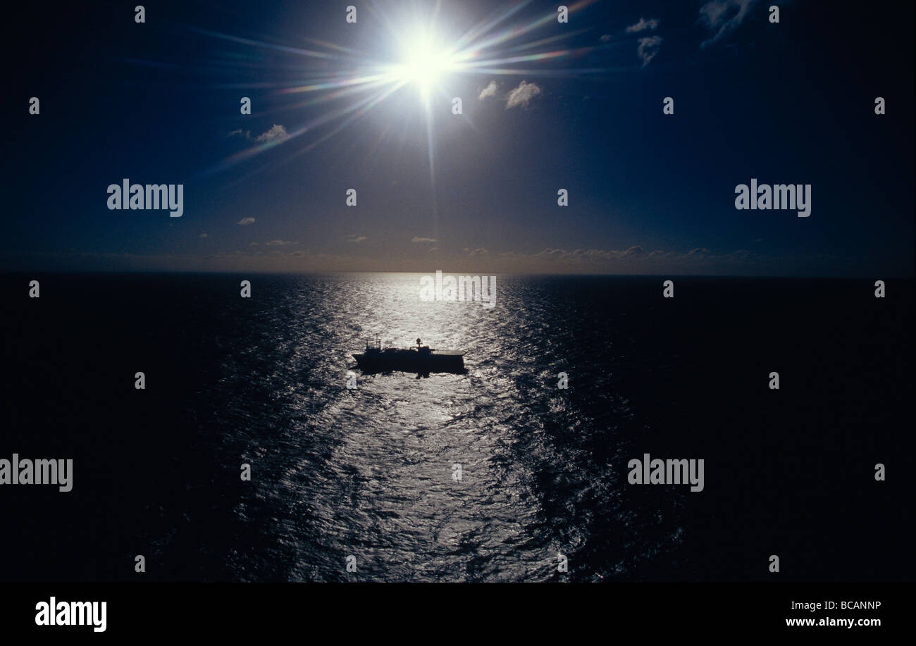 Un Geco Beta esplorazione sismica nave al tramonto su un vasto oceano calmo. Foto Stock