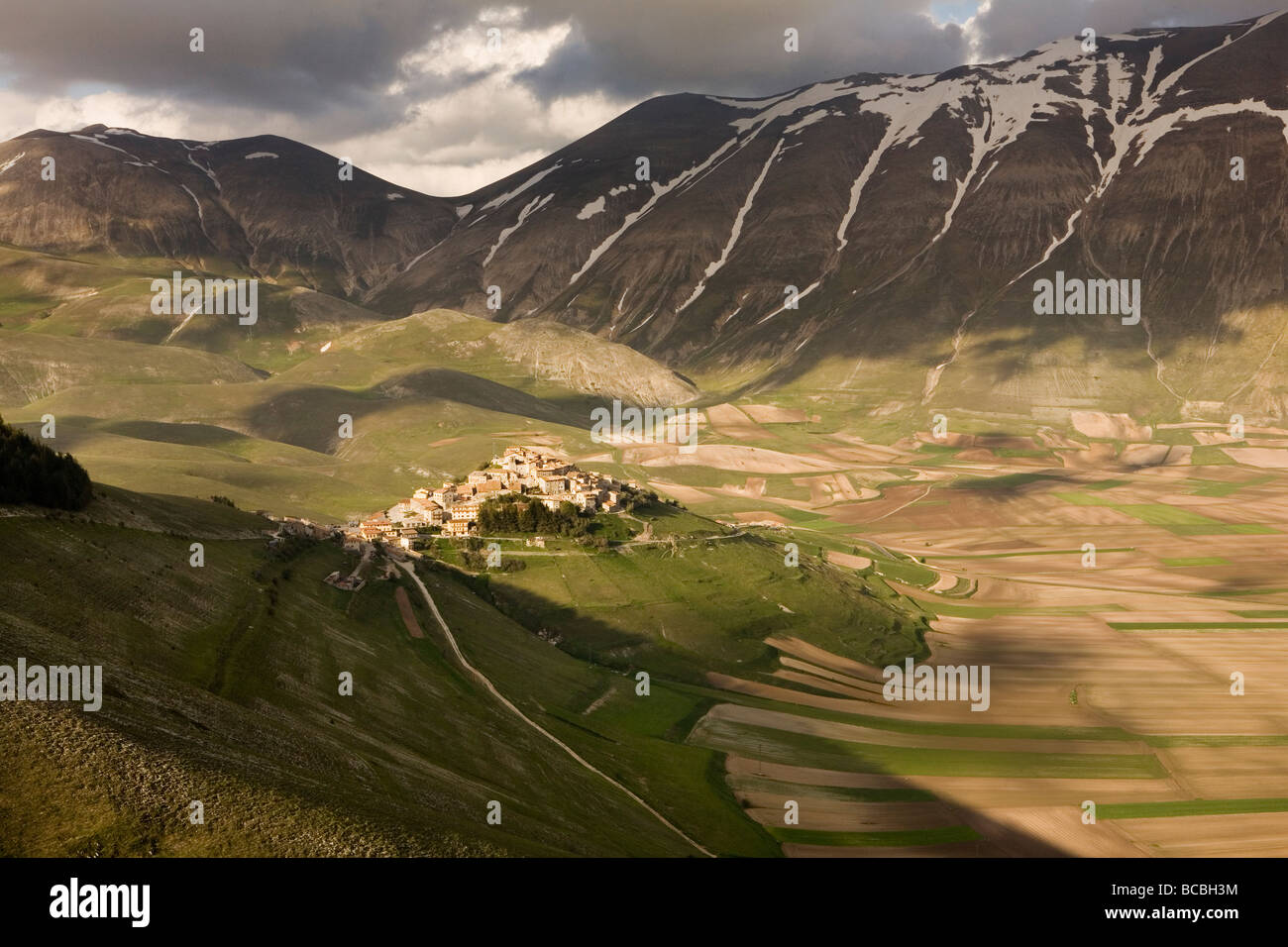 Piccola cittadina di Castelluccio in Umbria in Italia al tramonto in estate tempo nonostante la neve ancora aggrappati alla montagna Foto Stock