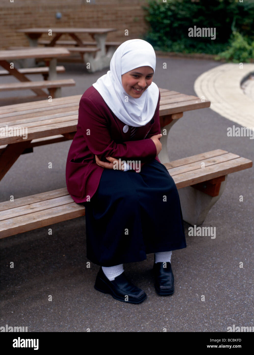 Ragazzina musulmana nel parco giochi seduta sul banco di lavoro Foto Stock