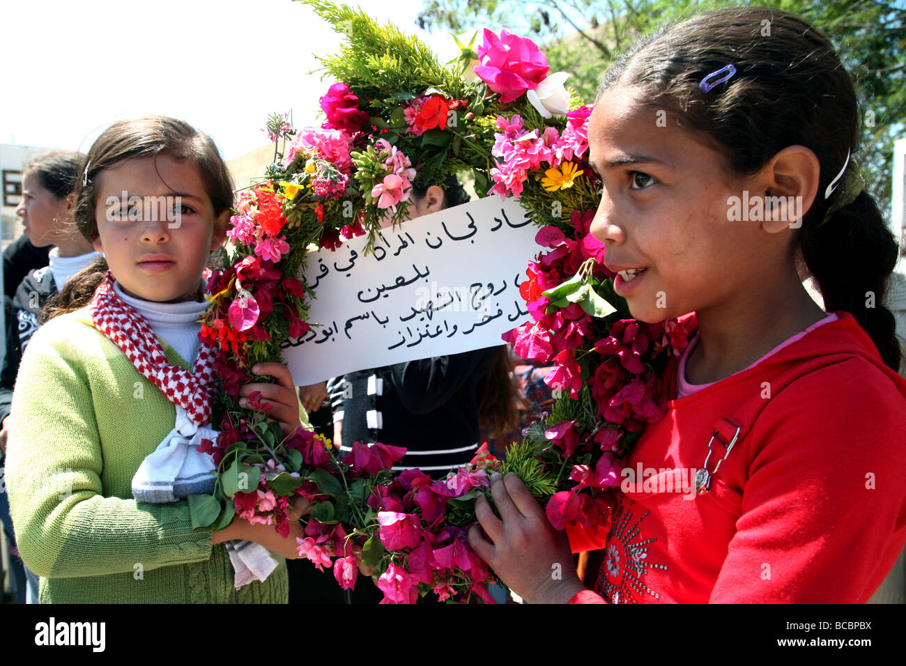 Le ragazze palestinesi tenendo una corona a un funerale in Cisgiordania villaggio di Bi'lin. Foto Stock