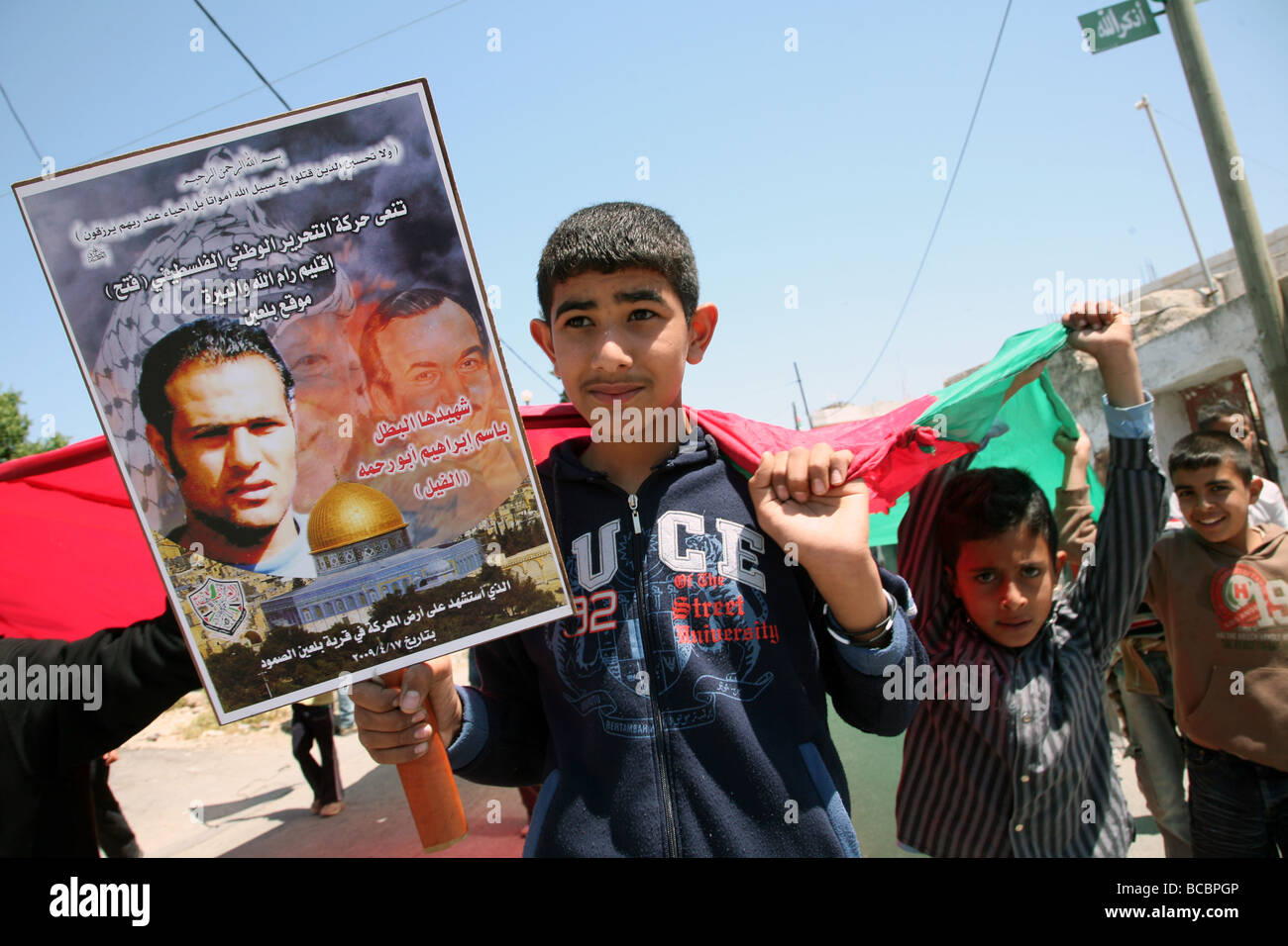 Un ragazzo palestinese trasporta un martire poster a un funerale in Cisgiordania villaggio di Bi'lin. Foto Stock