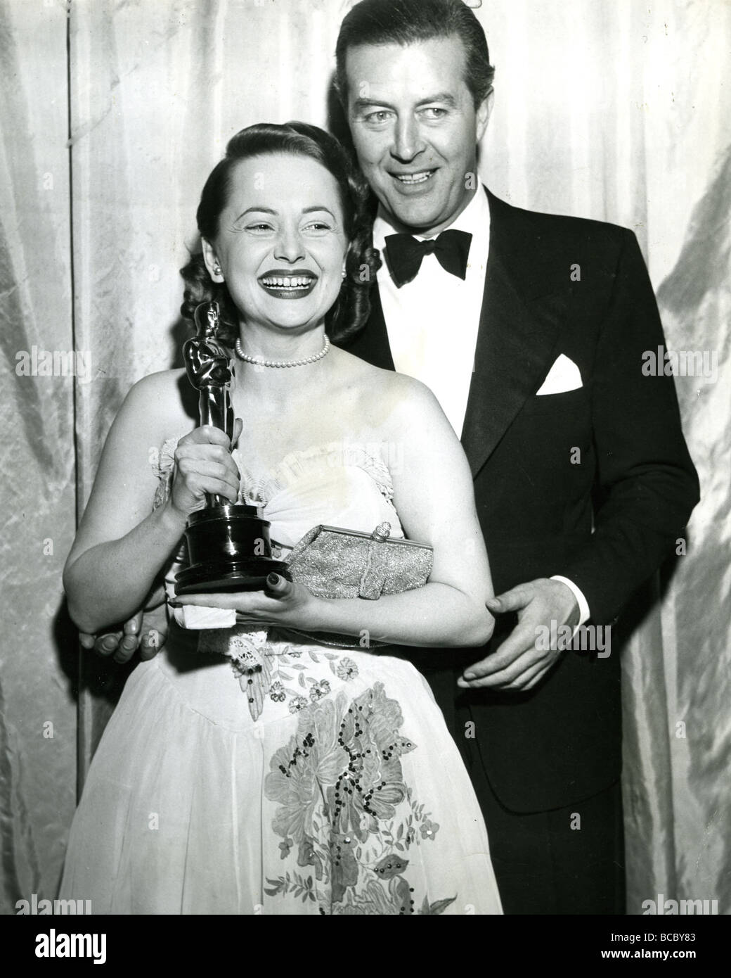 1947 Oscar - Olivia de Havilland riceve il suo trofeo come migliore attrice in a ciascuno il suo da Ray Milland Foto Stock