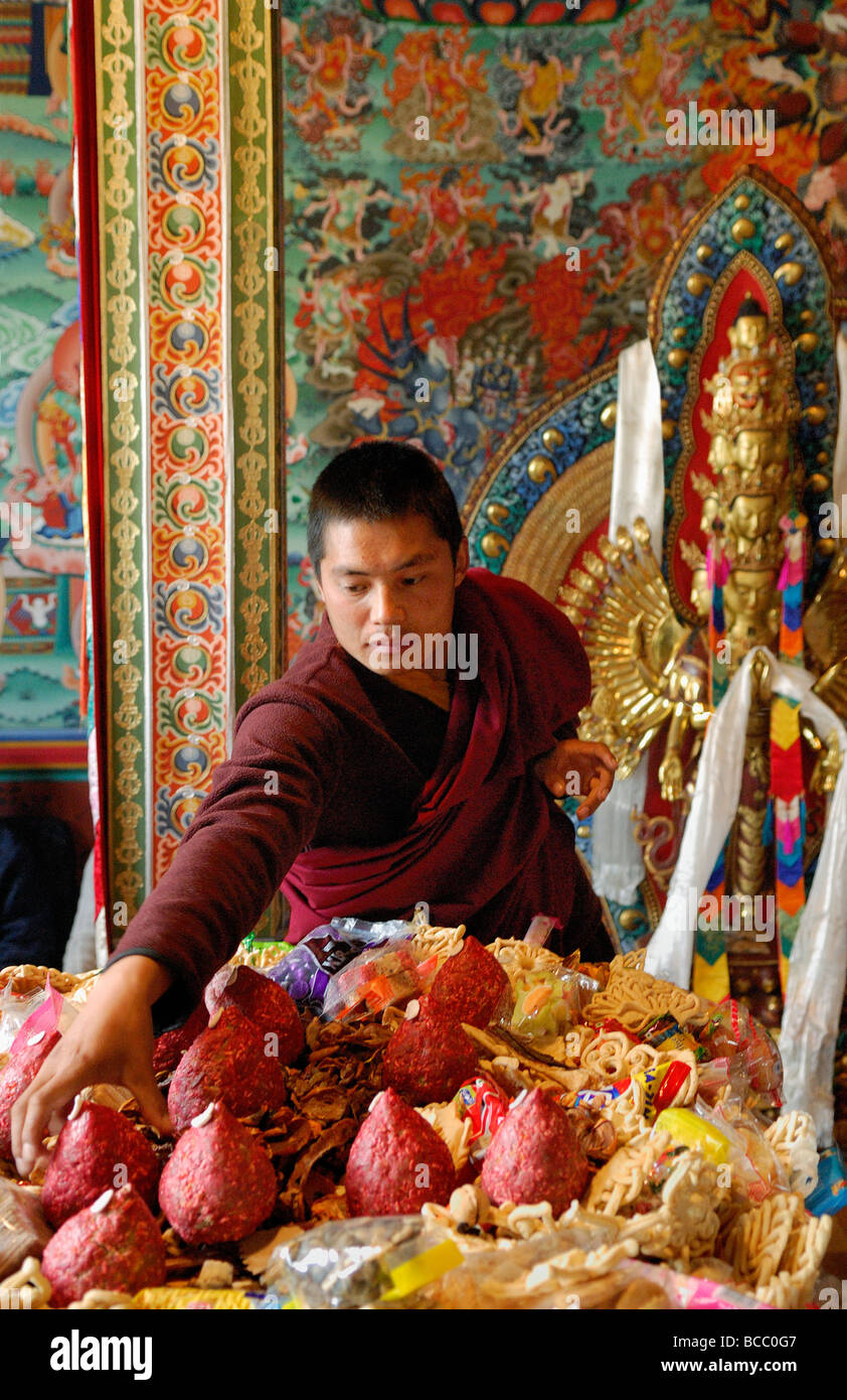 Il Bhutan, Thimphu, in una cappella privata, monaco buddista che offre luce per le divinità Foto Stock