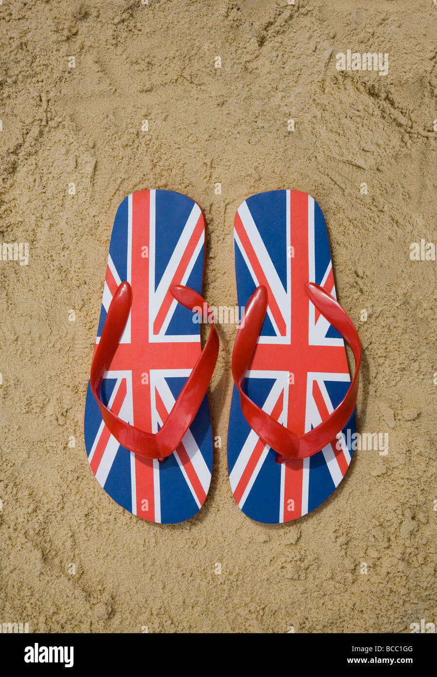 Unione jack flip-flop sulla spiaggia sabbiosa Foto Stock