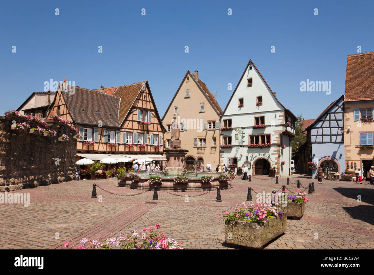 Scena di strada in Place du Chateau piazza nel pittoresco borgo medievale sulla strada del vino. Eguisheim Haut-Rhin Alsace Francia. Foto Stock