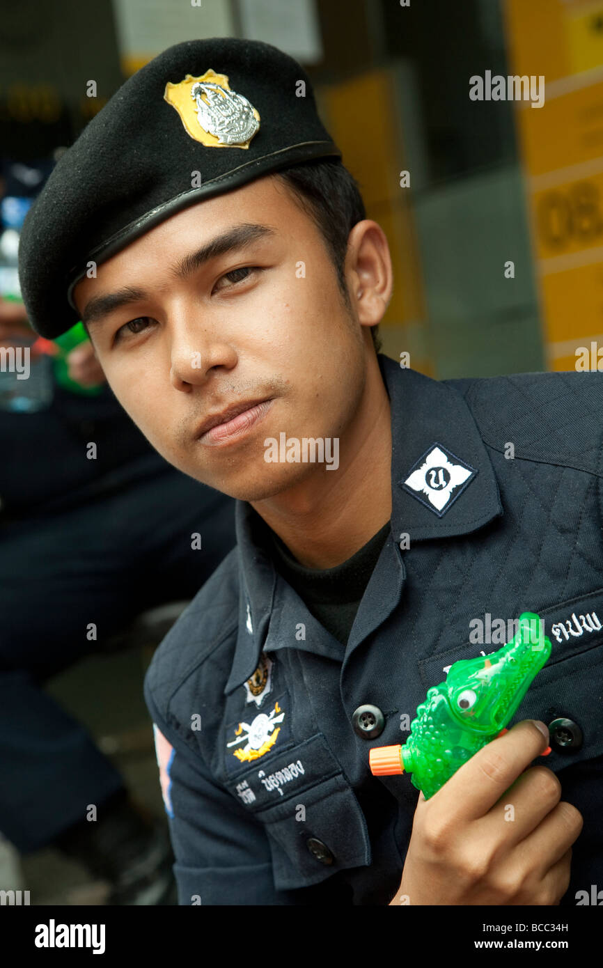 Bangkok, durante il Songkran il nuovo anno thailandese, le persone godono di invio e i giochi in acqua. Un soldato con una plastica pistola ad acqua Foto Stock