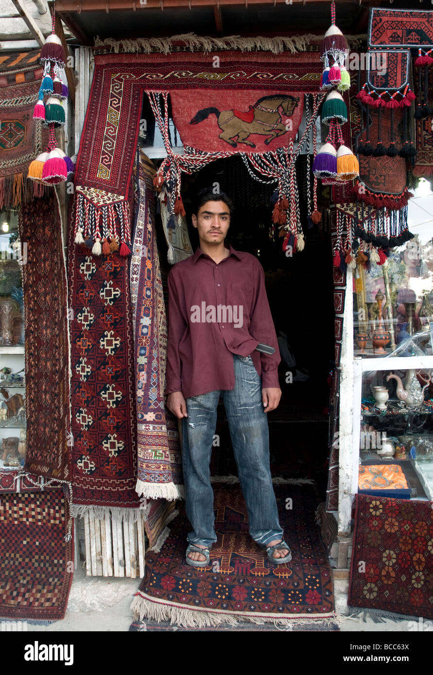 Un giovane venditore di tappeti nella porta di un negozio di tappeti a Kabul Foto Stock