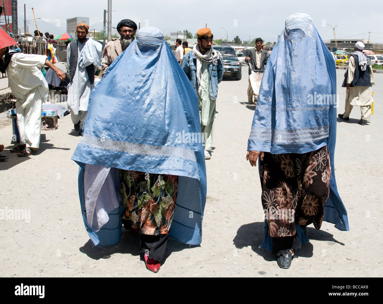 Due donne in una strada di Kabul indossare il consueto burqas blu che nascondono i loro volti ma parzialmente rivelare abbigliamento modesto sotto Foto Stock
