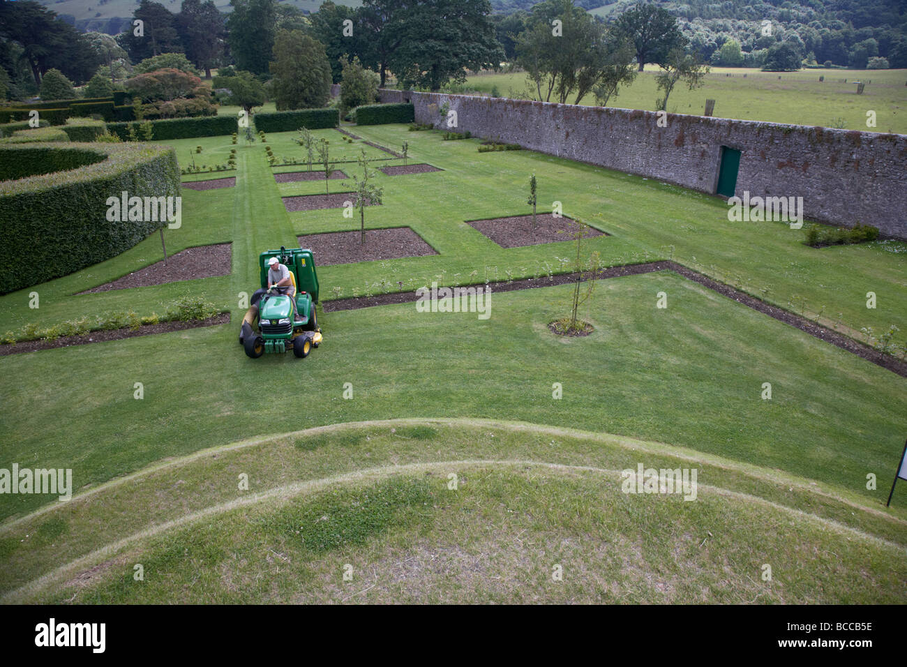 Giardiniere Falciare il prato del il giardino murato a Glenarm Castle nella contea di Antrim Irlanda del Nord Regno Unito Foto Stock