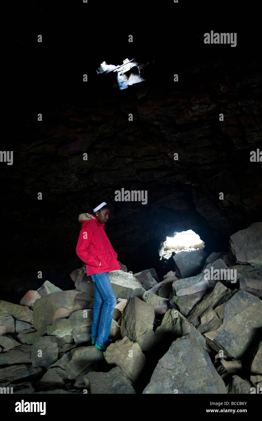 Ragazza adolescente in piedi all'interno di una grotta. Surtshellir grotta, Hallmundarhraun campo di lava, West Islanda. Foto Stock