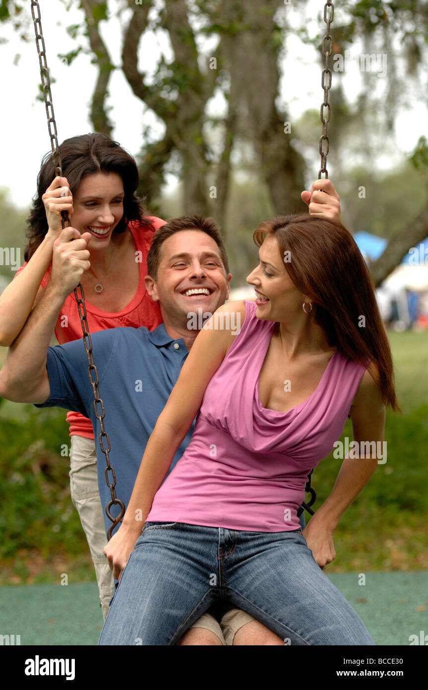Tre persone giovani adulti (25-35) ingannare intorno sul parco giochi altalena in Florida il parco di quartiere Foto Stock