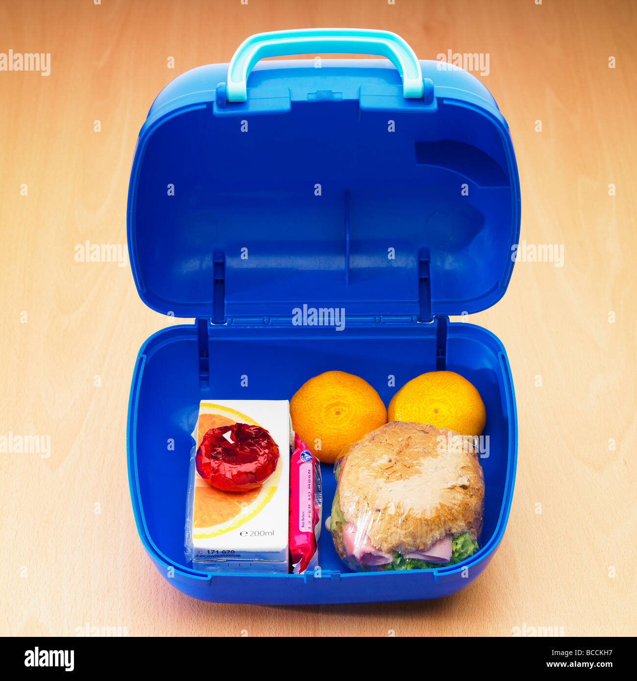 Un sano pranzo al sacco a scuola per bambini / pranzo al sacco con rotolo integrale, due frutta satsuma, formaggio leggero, succo d'arancia e un biscotto dolce. Foto Stock