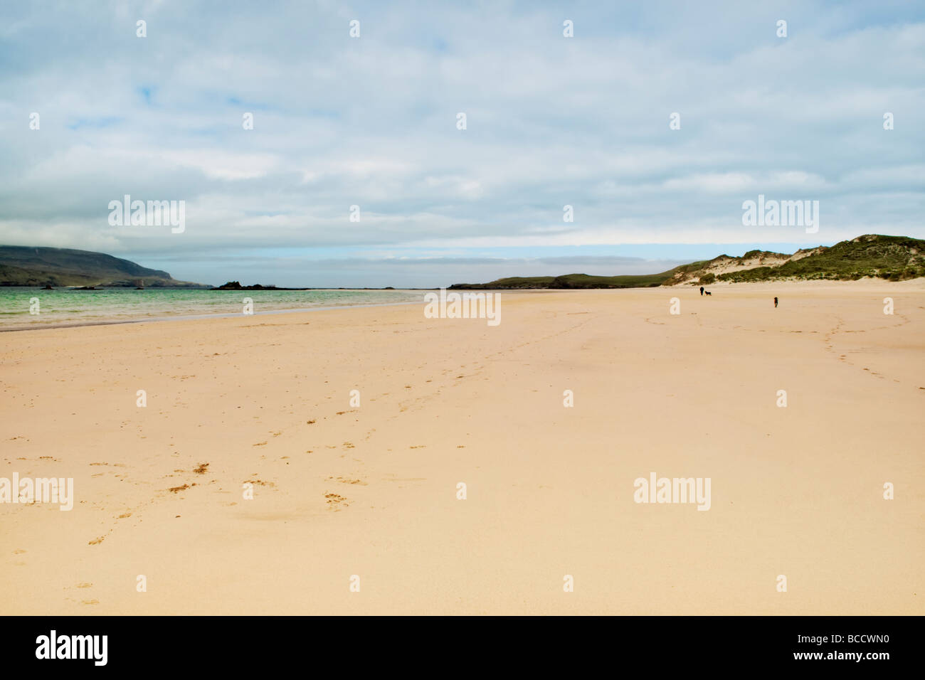 Spiaggia di sabbia e la baia di Balnakeil Bay, Durness, Sutherland in Scozia con uomo a camminare i cani a distanza Foto Stock