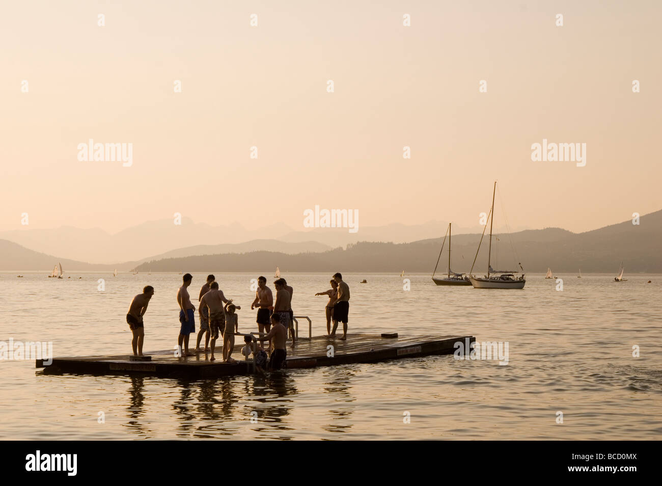 Gli adolescenti su un bacino galleggiante al crepuscolo, nuoto, Vancouver, British Columbia, Canada Foto Stock