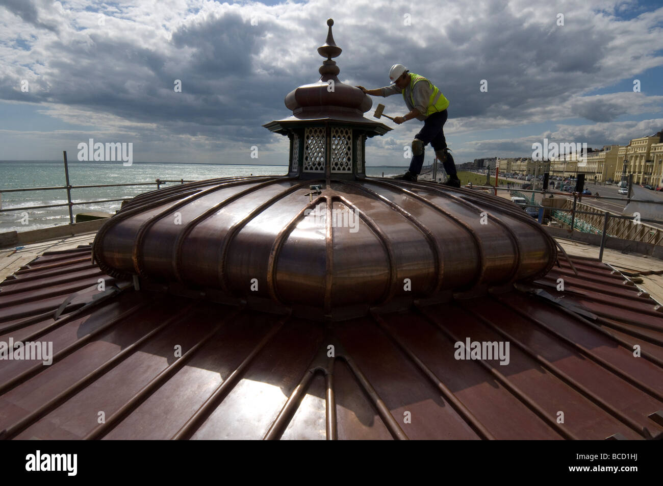 Un operaio martellare un nuovo tetto di rame su di un palco per spettacoli in stile vittoriano su Brighton e Hove lungomare Foto Stock