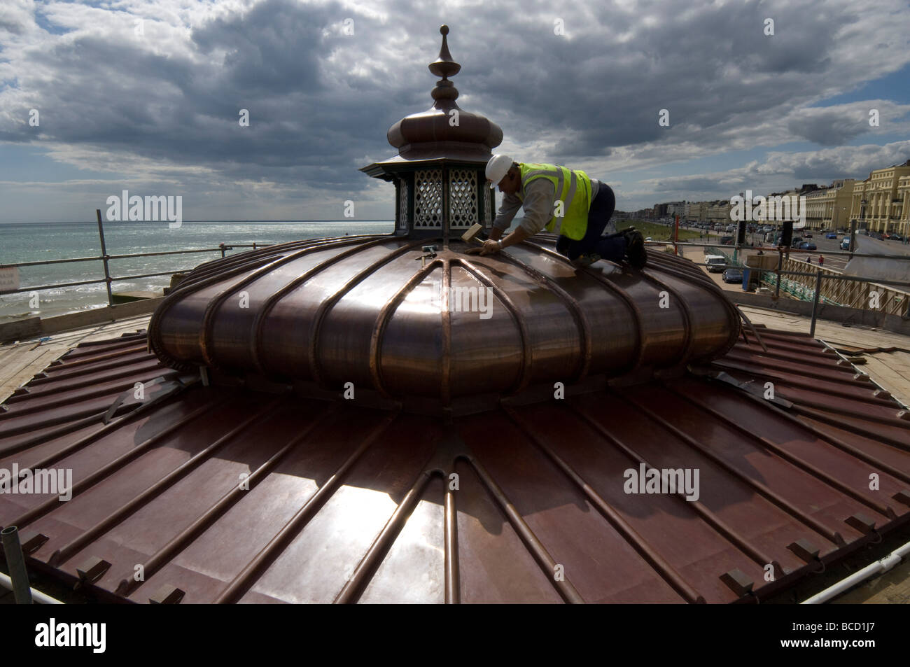 Un operaio martellare un nuovo tetto di rame su di un palco per spettacoli in stile vittoriano su Brighton e Hove lungomare Foto Stock