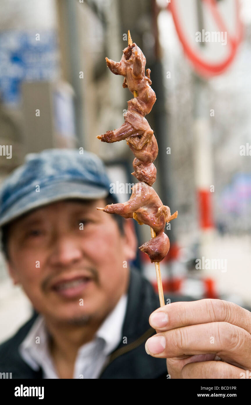 Un uomo con pulcini su uno spiedino Foto Stock