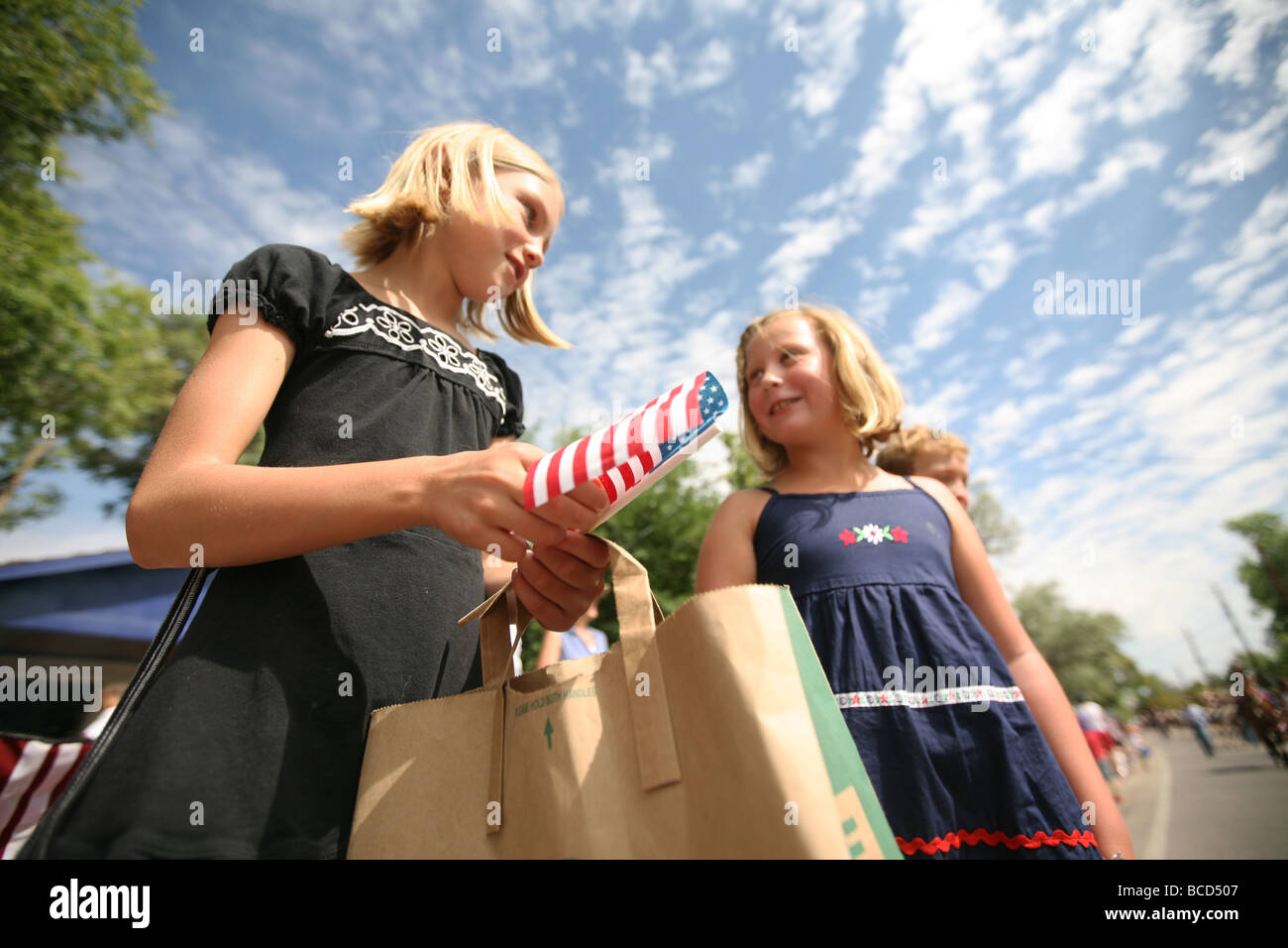 Due ragazze azienda noi bandiera al 4 di luglio parade Foto Stock