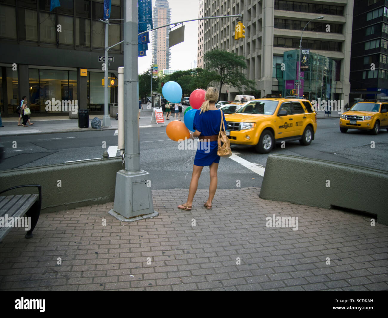 Giovane donna con palloncini attende di cross Broadway nella Upper West Side di New York Foto Stock