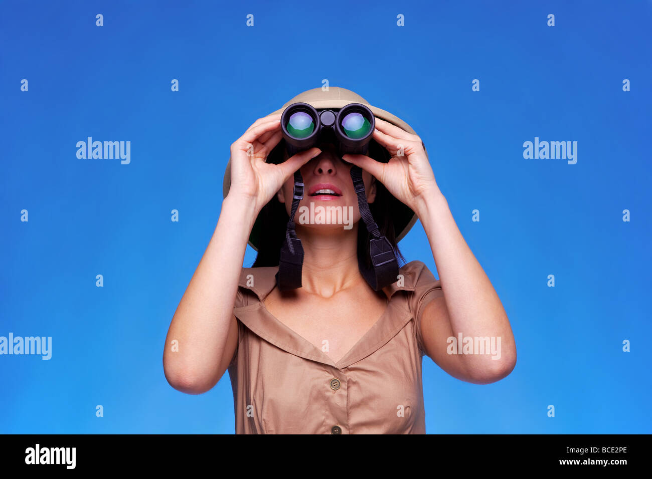 Una donna che indossa un casco albedo ricerca con un paio di binocoli sfondo blu con spazio di copia Foto Stock
