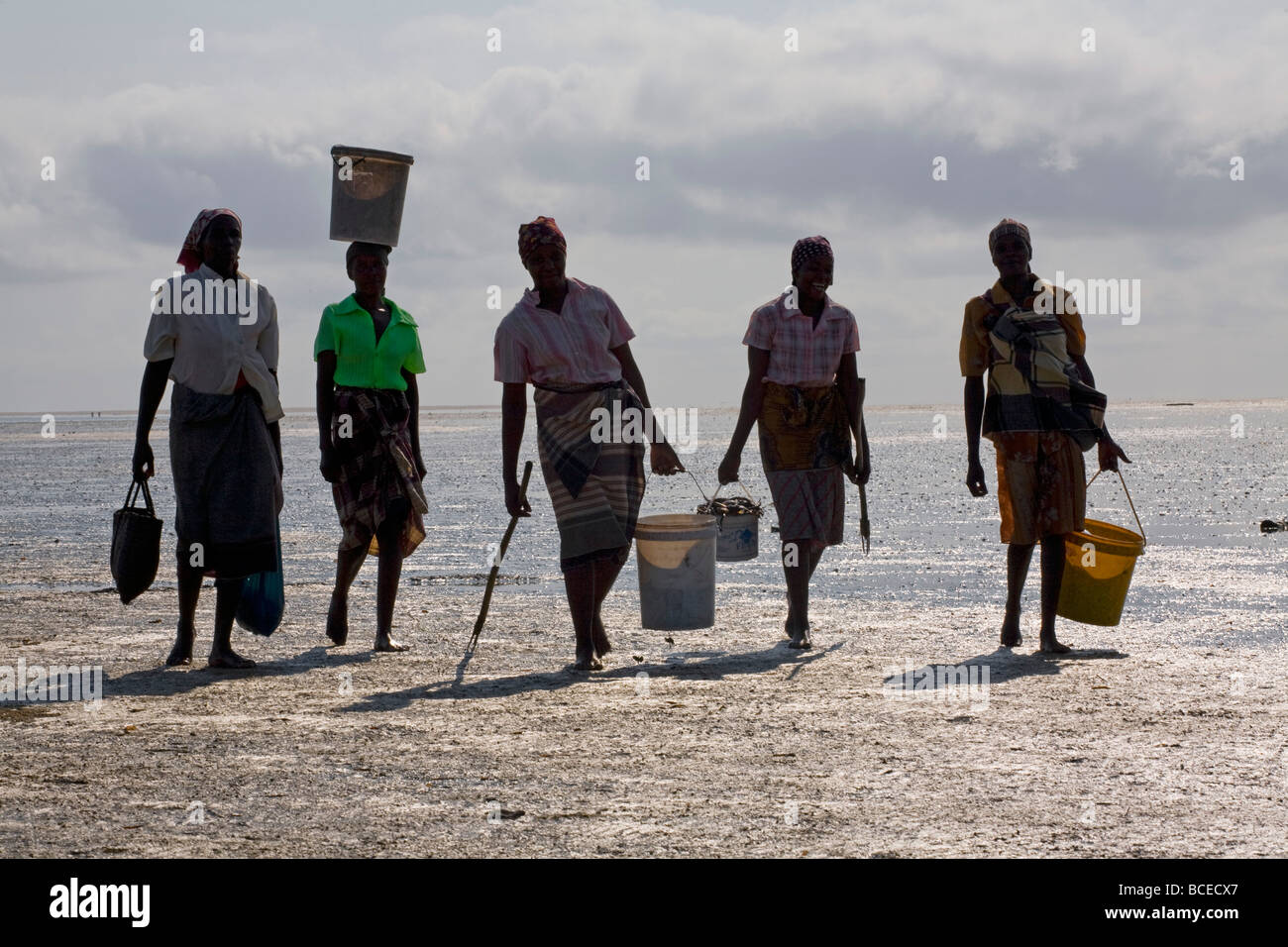 Mozambico, Inhaca Island. Onorevoli locali portano le loro catture di vongole al mattino presto con la bassa marea sulla spiaggia. Foto Stock