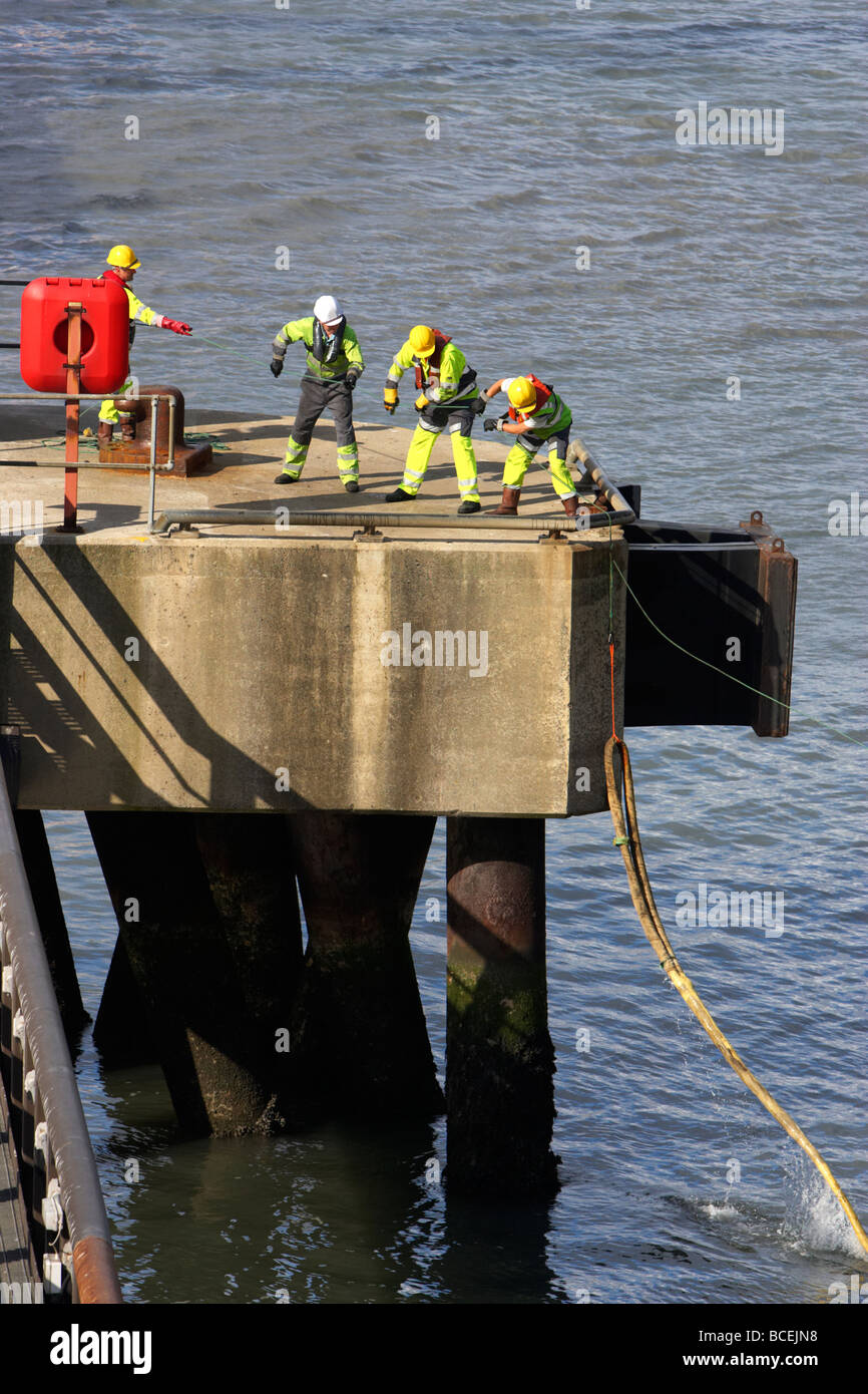 Shore equipaggio tirare la linea di sicurezza collegato alla fune della nave sulla banchina mentre l'ormeggio nel porto di Belfast Irlanda del Nord Regno Unito Foto Stock