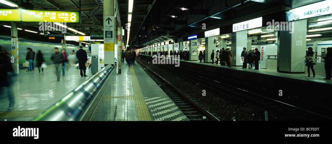 Pendolari attendere su piattaforme ferroviarie per la cattura di treni in metropolitana. Foto Stock