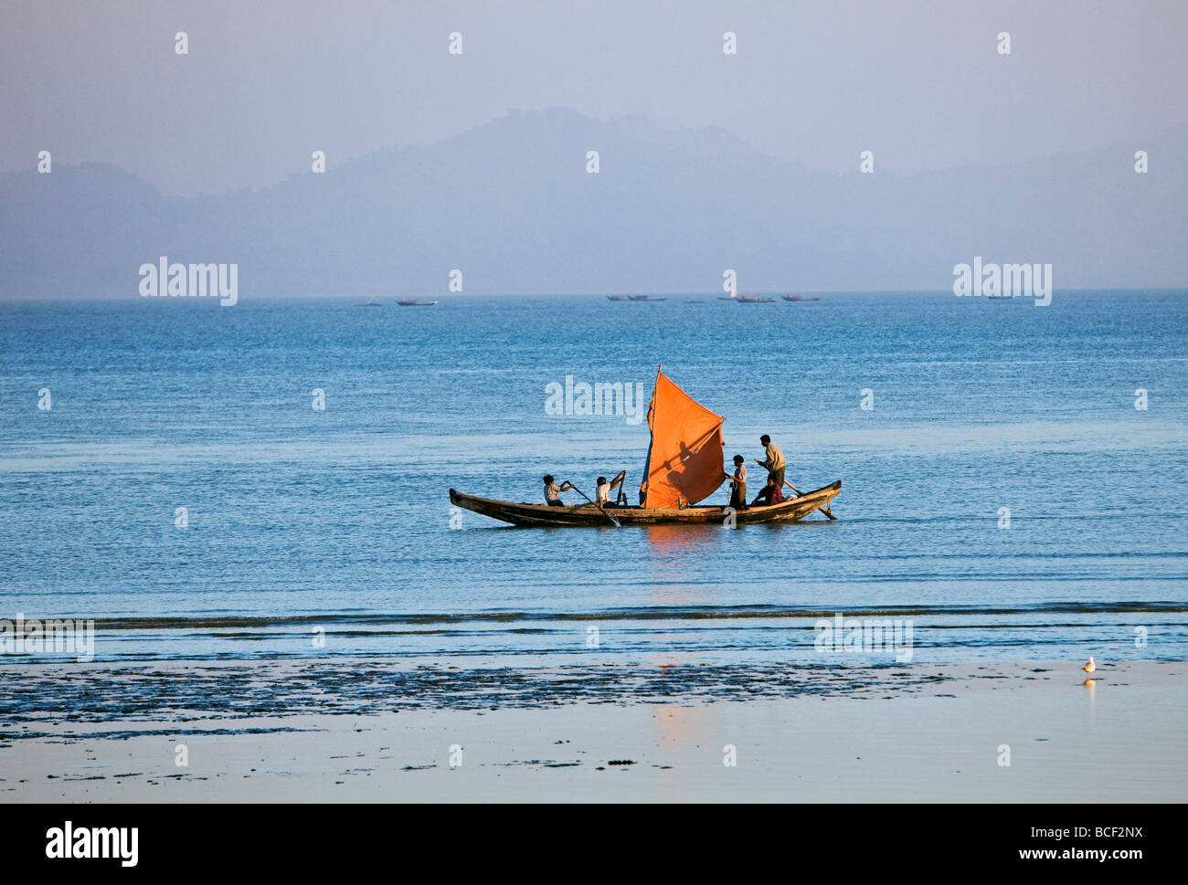 Myanmar Birmania, Stato di Rakhine. Come il sole tramonta dopo un giorno di blistering, l'equipaggio di una piccola barca da pesca hurries home. Foto Stock