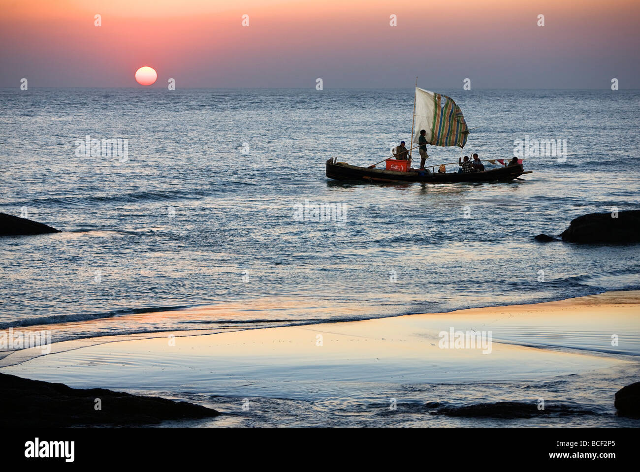 Myanmar Birmania, Stato di Rakhine. L'equipaggio di una barca da pesca hurries home di Sittwe come il sole tramonta sulla Baia del Bengala. Foto Stock