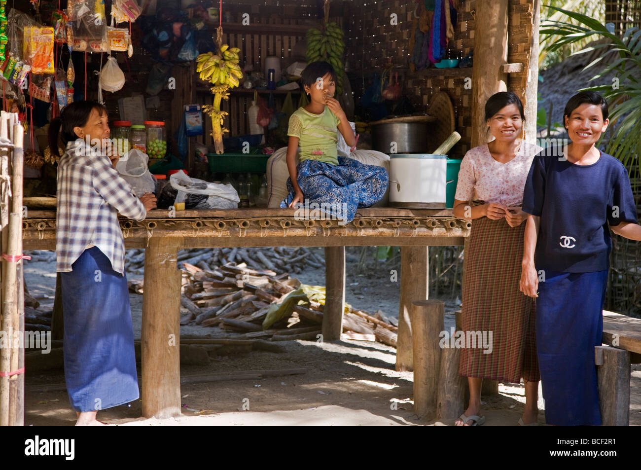 Myanmar Birmania, Fiume Kaladan. Donne birmane e una ragazza del Rakhine gruppo etnico presso il negozio del villaggio di Wa Bo. Foto Stock