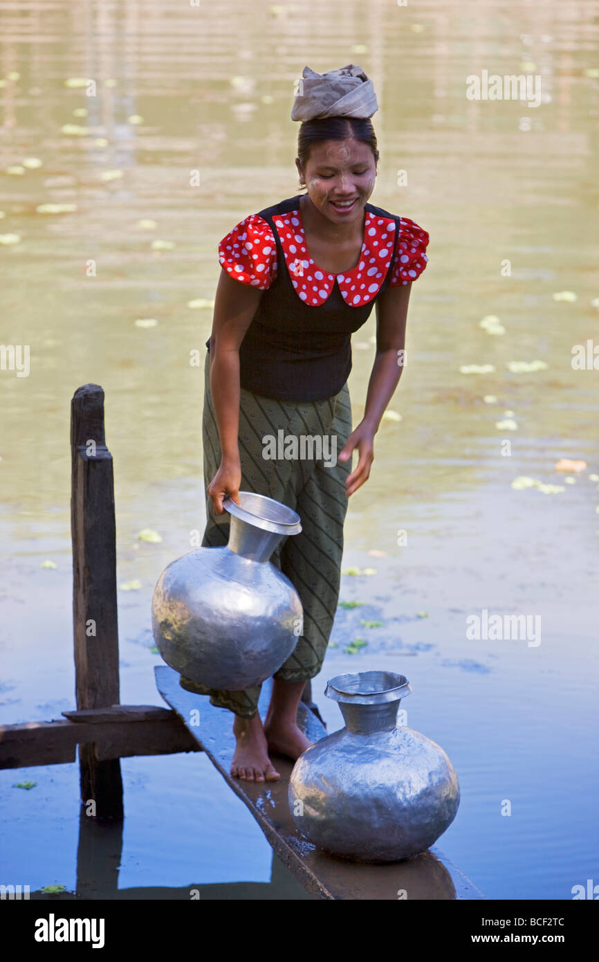 Myanmar Birmania Mrauk U. Una giovane donna Rakhine aspira acqua in pentole di alluminio da un laghetto di acqua piovana vicino al suo villaggio. Foto Stock