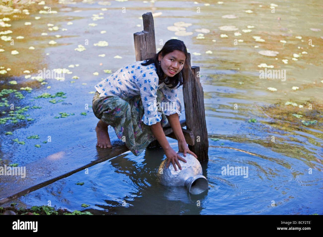 Myanmar Birmania Mrauk U. Una giovane donna Rakhine aspira acqua in una pentola in alluminio da un laghetto di acqua piovana vicino al suo villaggio. Foto Stock