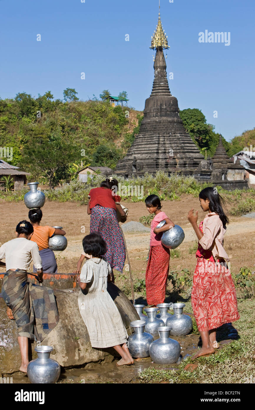 Myanmar Birmania Mrauk U. contro uno sfondo di antichi templi, Rakhine le donne attingere acqua da un pozzo a Mrauk brevetto statunitense n. Foto Stock
