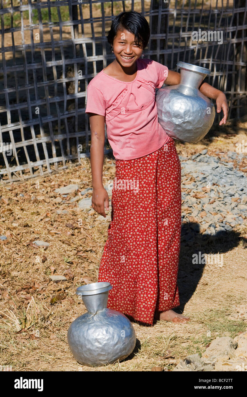 Myanmar Birmania Mrauk U. Una ragazza di Rakhine con alluminio contenitori di acqua a Mrauk U. importato da India e Bangladesh. Foto Stock