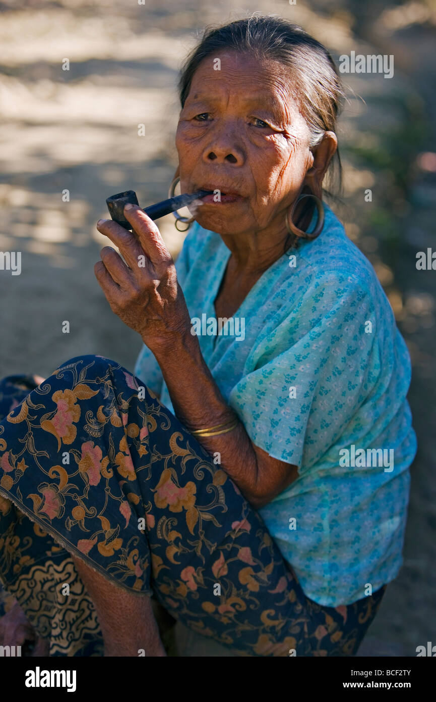 Myanmar Birmania Mrauk U. Una vecchia donna che fumare una tubazione in Mrauk U. che le donne che tradizionalmente si estendono il loro i lobi delle orecchie. Foto Stock