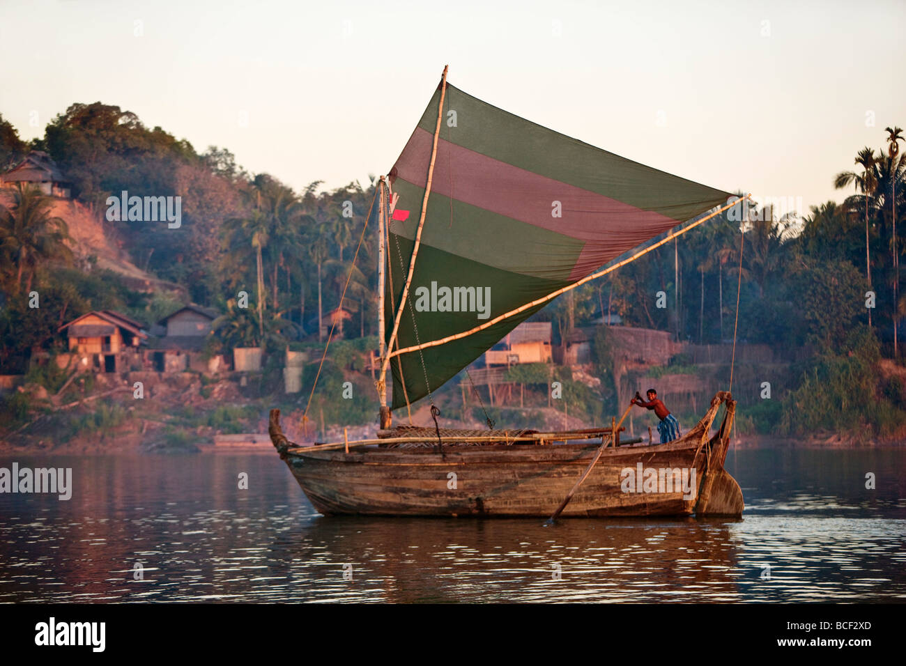Una grande barca in legno di design Rakhine vele fino il lay Myo nel fiume allo sbiadimento della luce della sera. Foto Stock