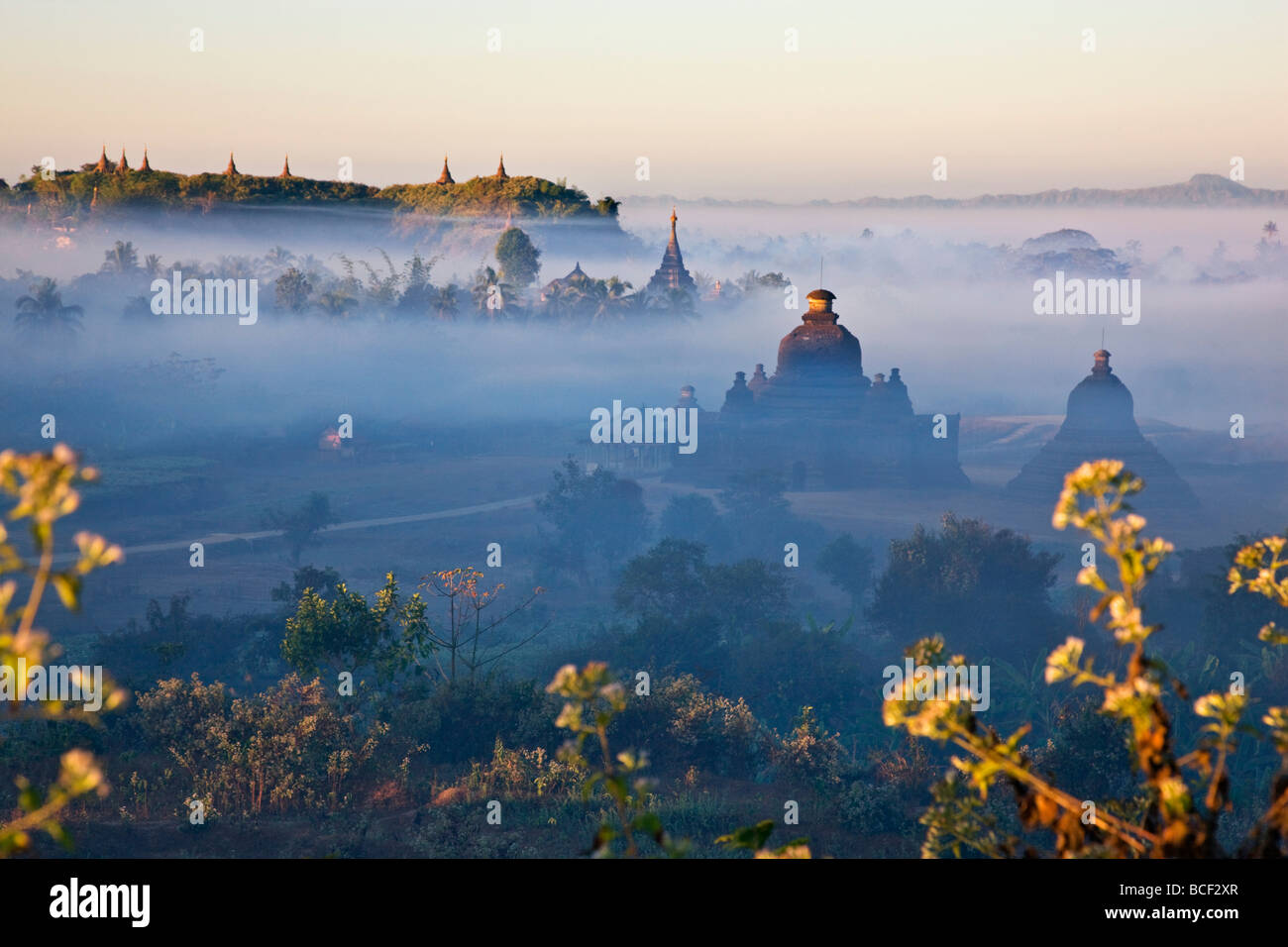 Come sorge il sole la mattina presto la nebbia avvolgenti la storica templi di Mrauk U inizia a sollevare. Foto Stock